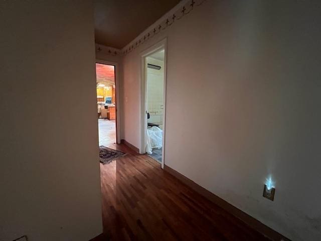 corridor featuring dark wood-style floors and baseboards