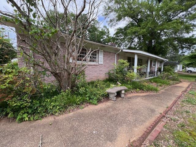 view of property exterior with a porch and brick siding