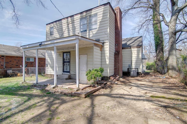 view of front of home featuring a chimney, fence, and dirt driveway