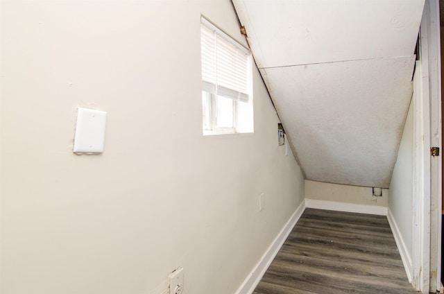 corridor with baseboards, lofted ceiling, and wood finished floors