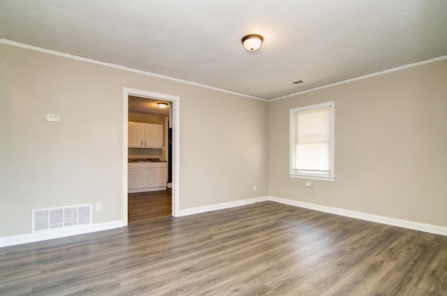 empty room featuring crown molding, wood finished floors, baseboards, and a textured ceiling