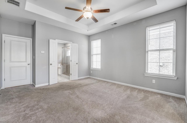 135 Briar Hollow Ln, Oakland, TN 38060 - unfurnished bedroom featuring a tray ceiling, light colored carpet, baseboards, and connected bathroom