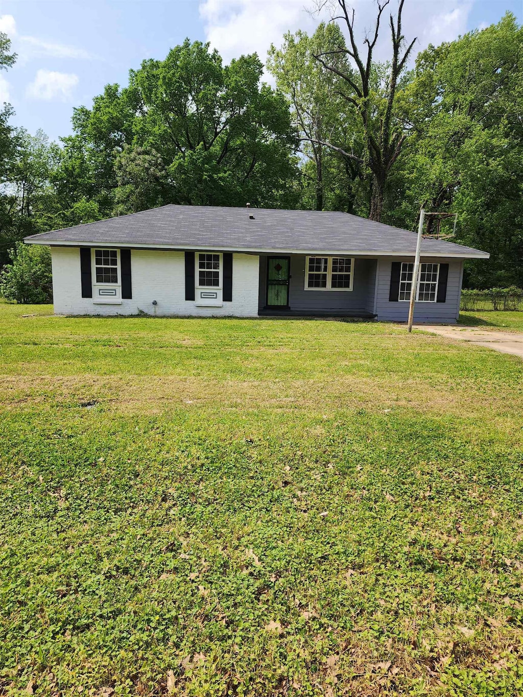 4785 Haleville Rd, Memphis, TN 38611 - ranch-style house featuring a front lawn and view of wooded area