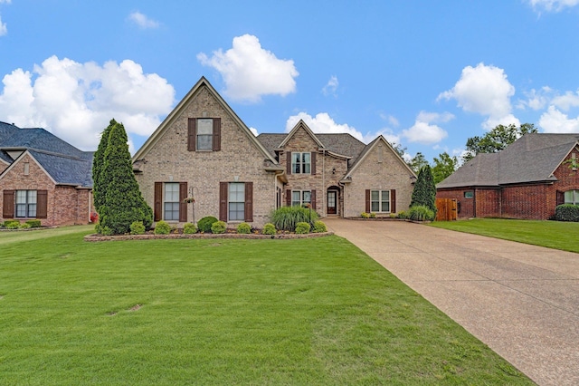 view of front of house with a front yard, concrete driveway, and brick siding