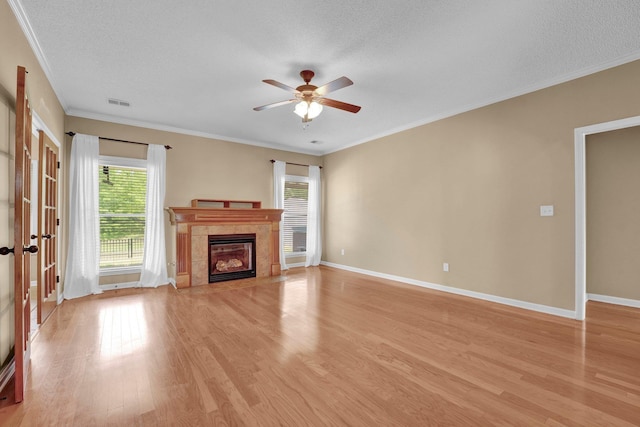 unfurnished living room featuring plenty of natural light, a ceiling fan, light wood-style floors, baseboards, and a textured ceiling