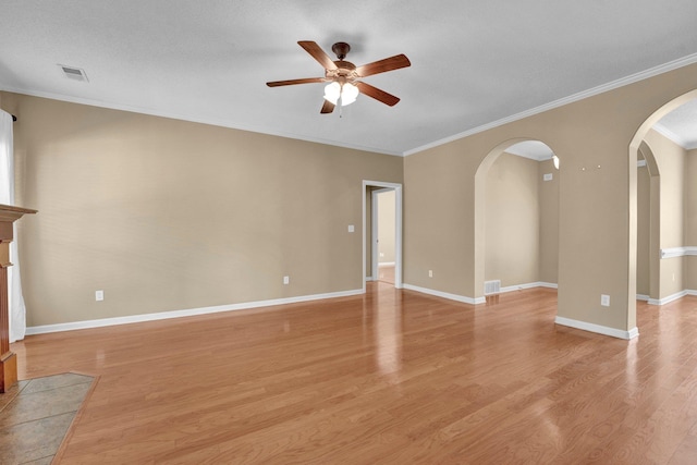 unfurnished living room featuring ceiling fan, arched walkways, light wood-type flooring, ornamental molding, and baseboards