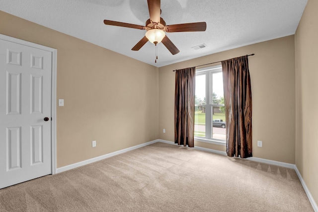 carpeted spare room with a ceiling fan, baseboards, and a textured ceiling