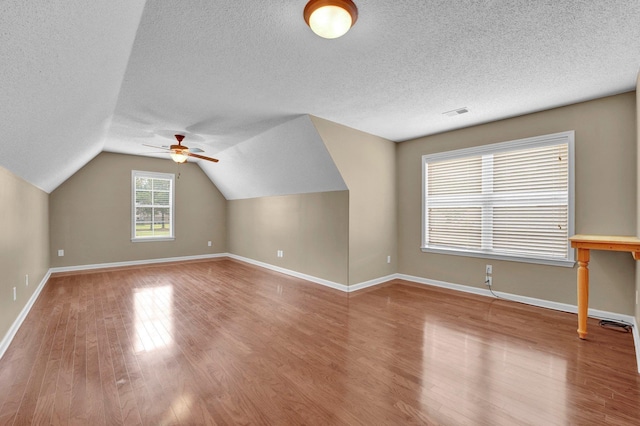 additional living space featuring a textured ceiling, wood finished floors, ceiling fan, lofted ceiling, and baseboards