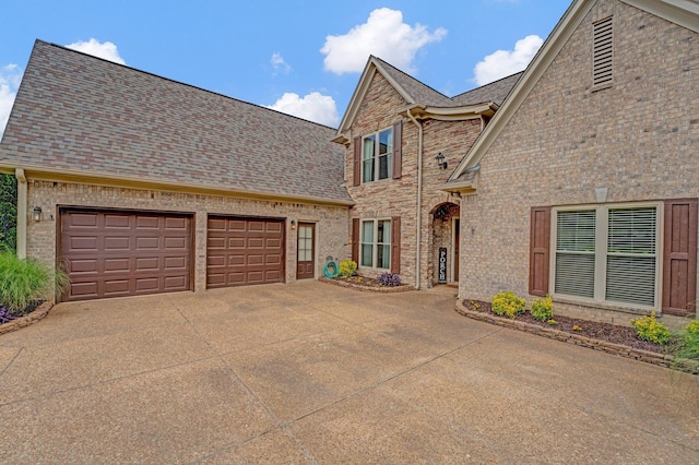 view of front of property with concrete driveway, a garage, brick siding, and roof with shingles
