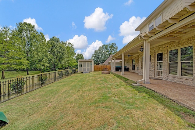 view of yard featuring a storage shed, a ceiling fan, a patio, and an outbuilding
