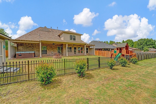 back of property with a hot tub and a playground