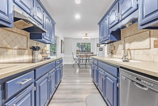 kitchen featuring dishwasher, blue cabinetry, black electric stovetop, under cabinet range hood, and a sink