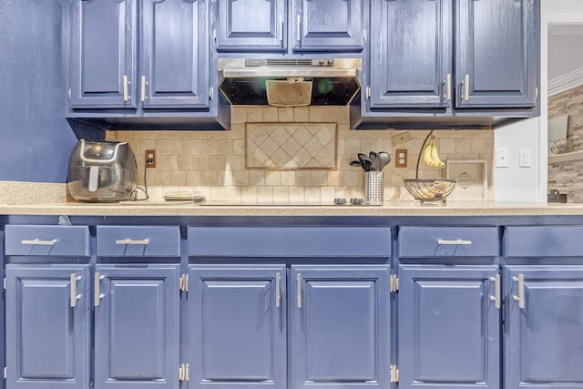 kitchen featuring blue cabinets, under cabinet range hood, light countertops, and backsplash