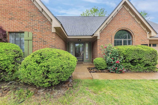entrance to property featuring roof with shingles and brick siding