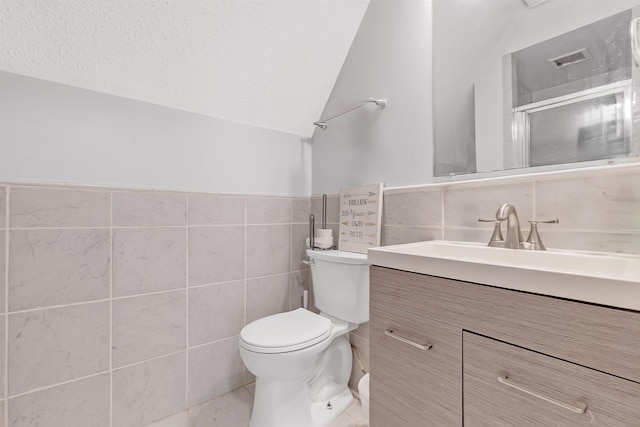 full bath featuring tile walls, toilet, vanity, a shower with shower door, and a textured ceiling