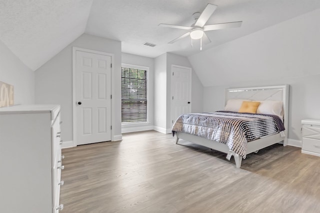 bedroom featuring lofted ceiling, light wood finished floors, baseboards, and ceiling fan