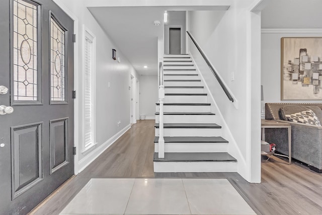foyer with wood finished floors, stairway, and baseboards