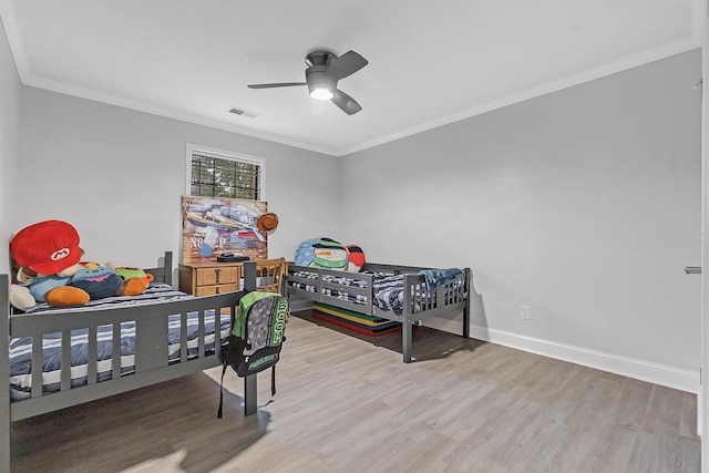 bedroom featuring wood finished floors, crown molding, baseboards, and a ceiling fan