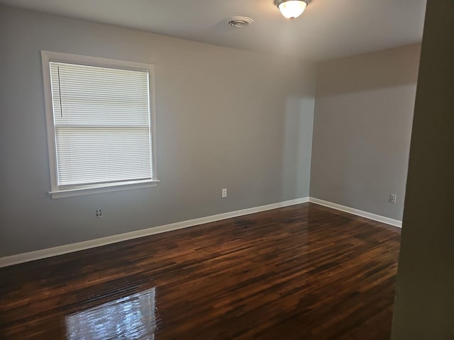 spare room with dark wood-style flooring and baseboards