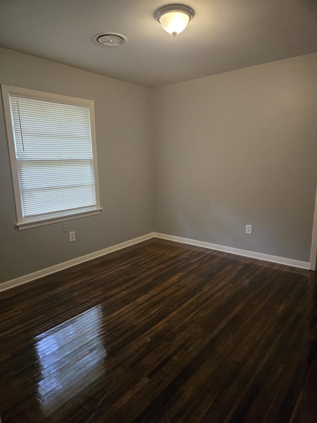 empty room with baseboards and dark wood finished floors