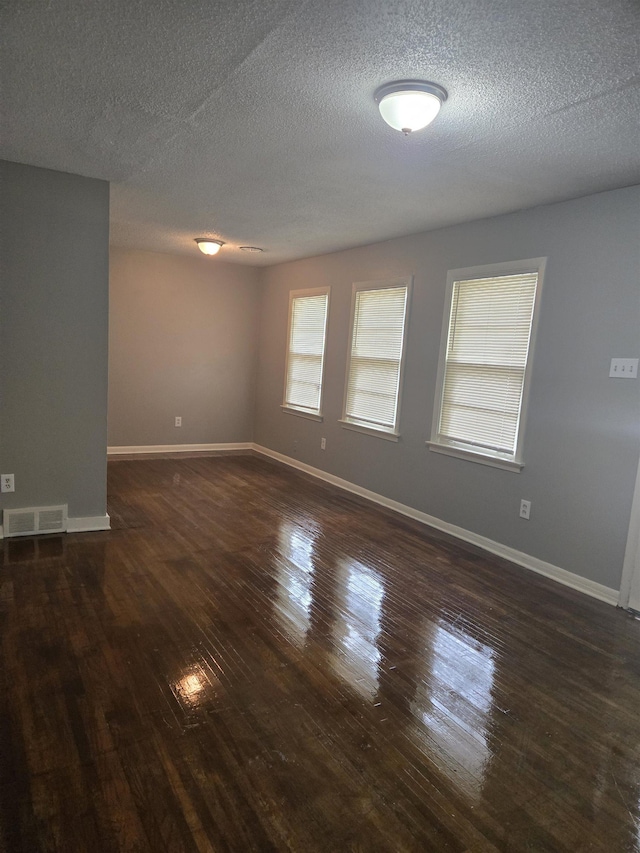 unfurnished room featuring dark wood-style floors, baseboards, and a textured ceiling