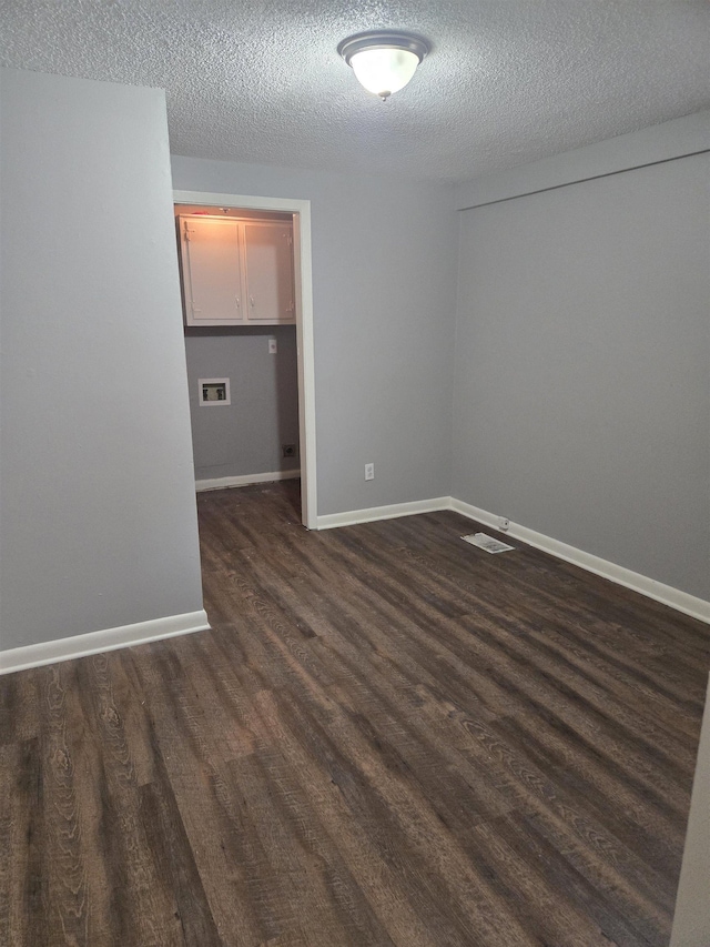 unfurnished room featuring dark wood finished floors, a textured ceiling, and baseboards