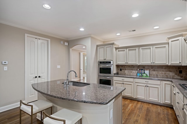 984 Russell Farms Rd, Collierville, TN 38017 - kitchen featuring a sink, stainless steel double oven, arched walkways, backsplash, and dark stone counters
