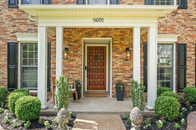 entrance to property with brick siding and a porch
