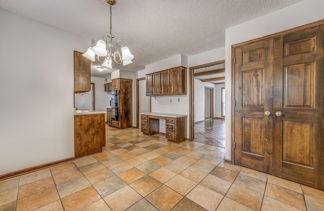 kitchen featuring a chandelier, light countertops, a textured ceiling, baseboards, and decorative light fixtures