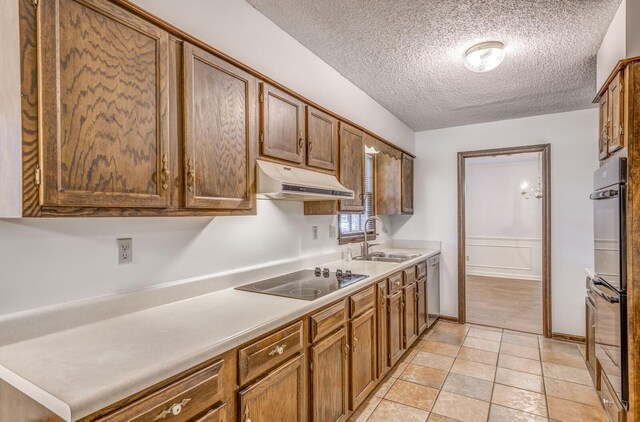 kitchen with a sink, under cabinet range hood, black appliances, a textured ceiling, and light countertops