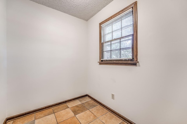 unfurnished room with a textured ceiling and baseboards