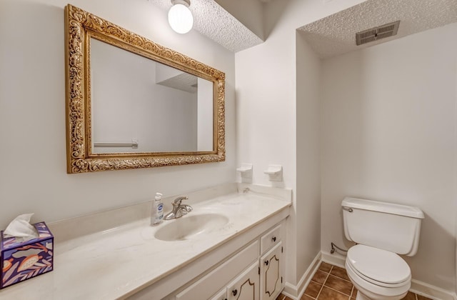 half bathroom featuring toilet, tile patterned floors, vanity, a textured ceiling, and baseboards