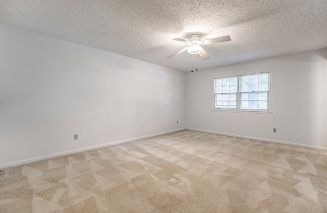 spare room with a textured ceiling, ceiling fan, light colored carpet, and baseboards