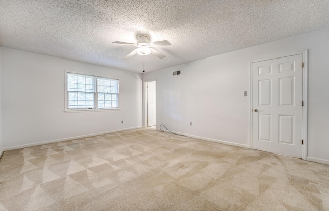 unfurnished room featuring a ceiling fan, a textured ceiling, light colored carpet, and baseboards