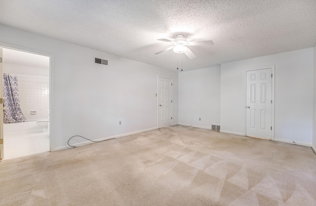 unfurnished bedroom with carpet floors, a textured ceiling, ensuite bathroom, baseboards, and ceiling fan