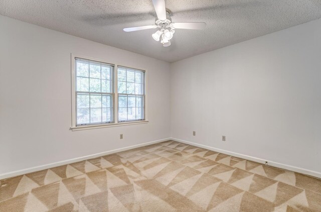 empty room featuring light carpet, a textured ceiling, a ceiling fan, and baseboards