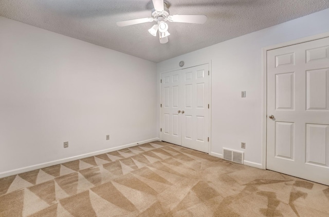 unfurnished bedroom featuring light colored carpet, a textured ceiling, baseboards, and ceiling fan