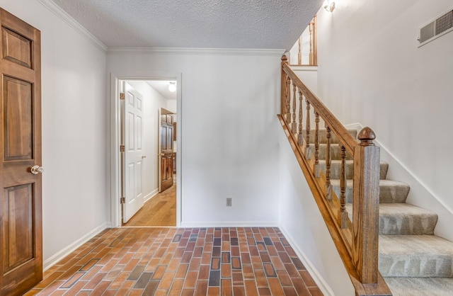 stairway featuring baseboards, a textured ceiling, brick floors, and crown molding