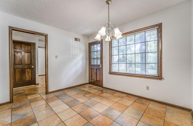 unfurnished dining area with a chandelier, a textured ceiling, and baseboards
