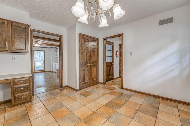 unfurnished dining area featuring a textured ceiling, baseboards, and a chandelier