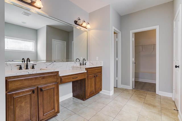 bathroom featuring double vanity, tile patterned flooring, and a walk in closet