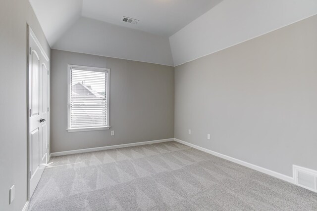 unfurnished room featuring light carpet, baseboards, and lofted ceiling