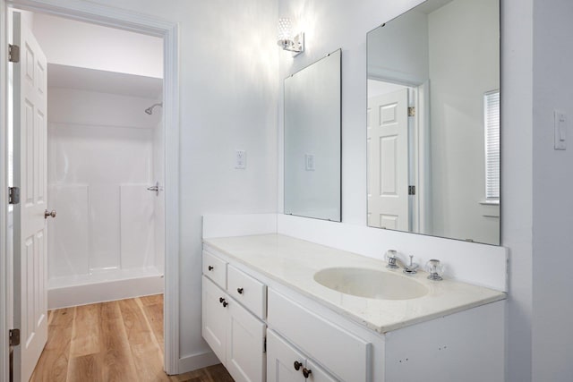 bathroom featuring a shower, wood finished floors, and vanity