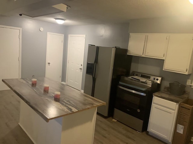kitchen with stainless steel range with electric stovetop, fridge with ice dispenser, white cabinets, light wood-style flooring, and a kitchen island