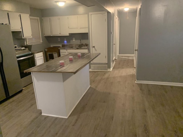 kitchen with stainless steel range with electric stovetop, white cabinets, light wood-style floors, and baseboards