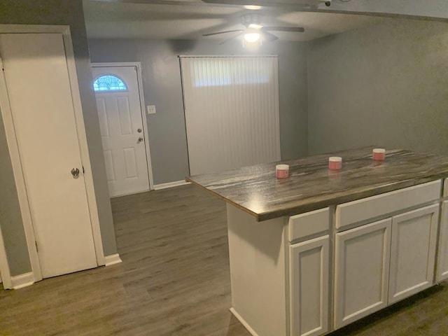 kitchen with ceiling fan, wood finished floors, baseboards, white cabinets, and dark countertops