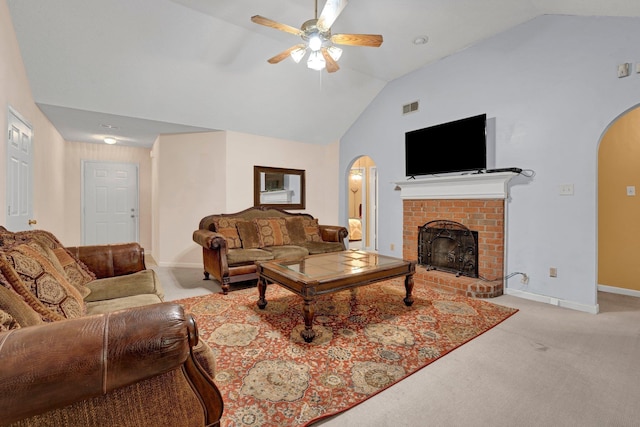living room with arched walkways, vaulted ceiling, a ceiling fan, light colored carpet, and a fireplace
