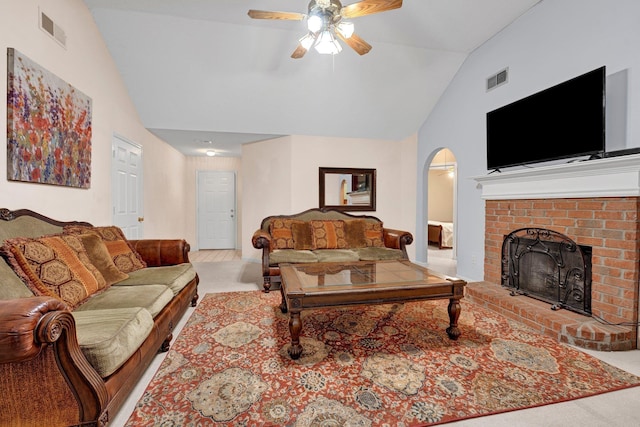 carpeted living area with arched walkways, ceiling fan, a brick fireplace, and high vaulted ceiling