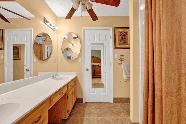 bathroom featuring a ceiling fan, double vanity, tile patterned floors, a textured ceiling, and ensuite bath