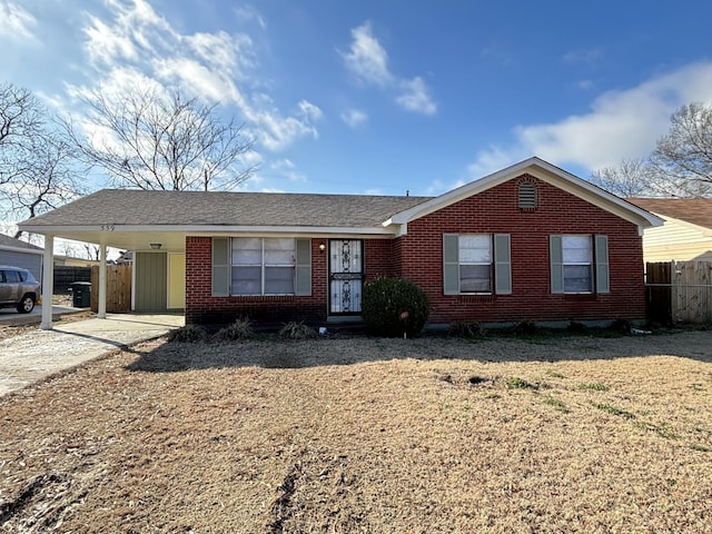 single story home featuring brick siding, fence, an attached carport, and driveway
